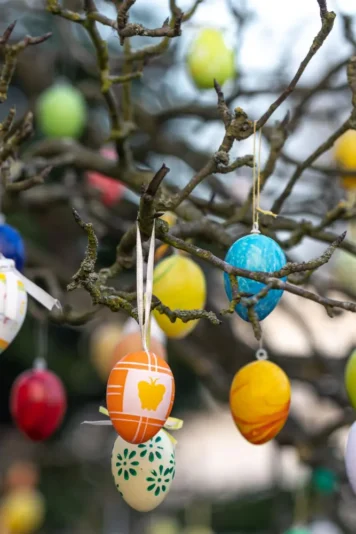 Árvore de Páscoa decorada com ovos coloridos, símbolo da tradição da Páscoa na Alemanha. A árvore exibe enfeites vibrantes em galhos secos, trazendo um toque festivo e alegre para a celebração