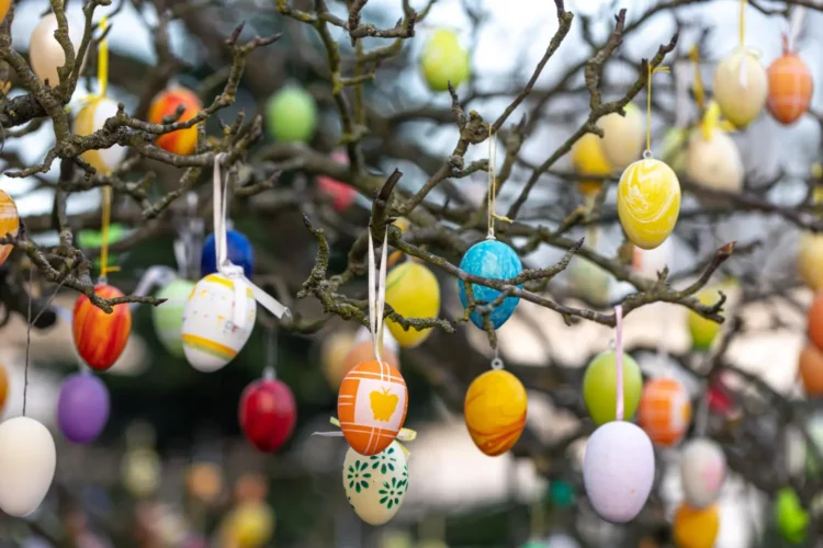 Árvore de Páscoa decorada com ovos coloridos, símbolo da tradição da Páscoa na Alemanha. A árvore exibe enfeites vibrantes em galhos secos, trazendo um toque festivo e alegre para a celebração