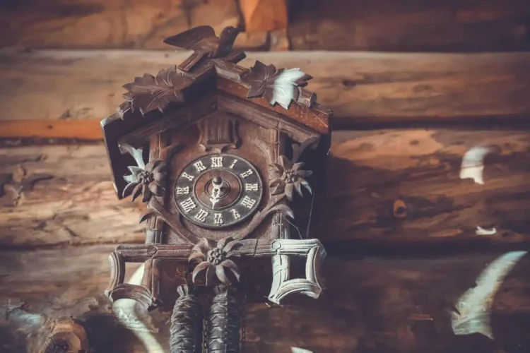 Relógio cuco tradicional em ambiente de decoração rústica, com paredes de madeira e baixa iluminação, destacando o charme clássico do estilo.