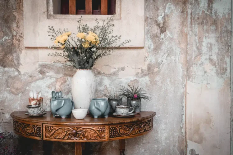 A imagem traz exemplos do estilo vintage na decoração, com vaso decorativo e objetos antigos sobre uma mesa de madeira.